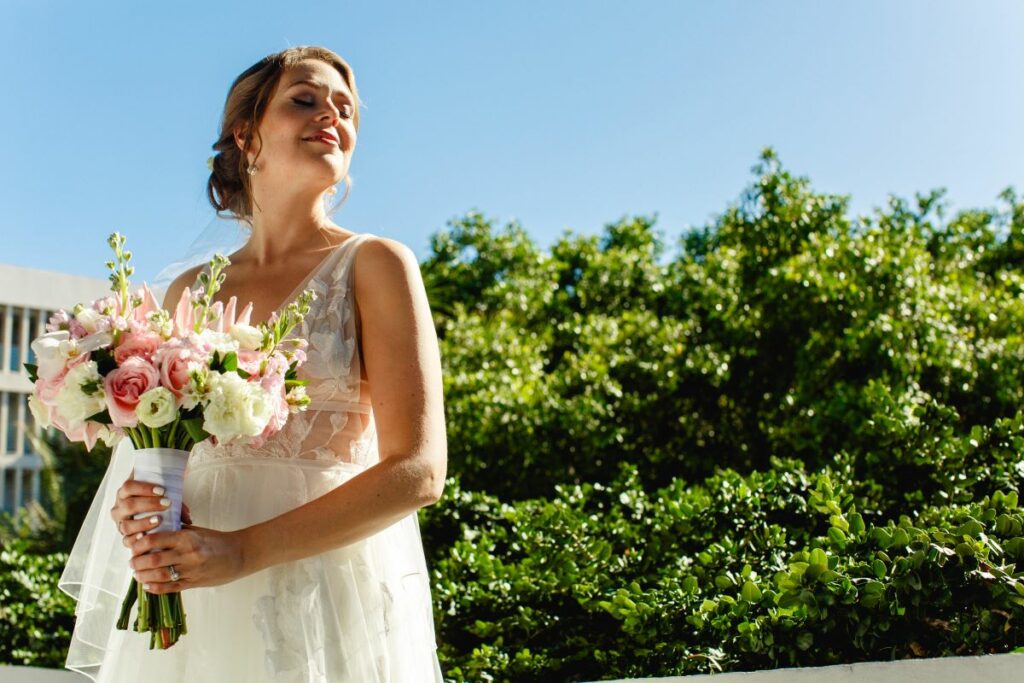 Smilling bride holding her flower bouquet in a lush garden
