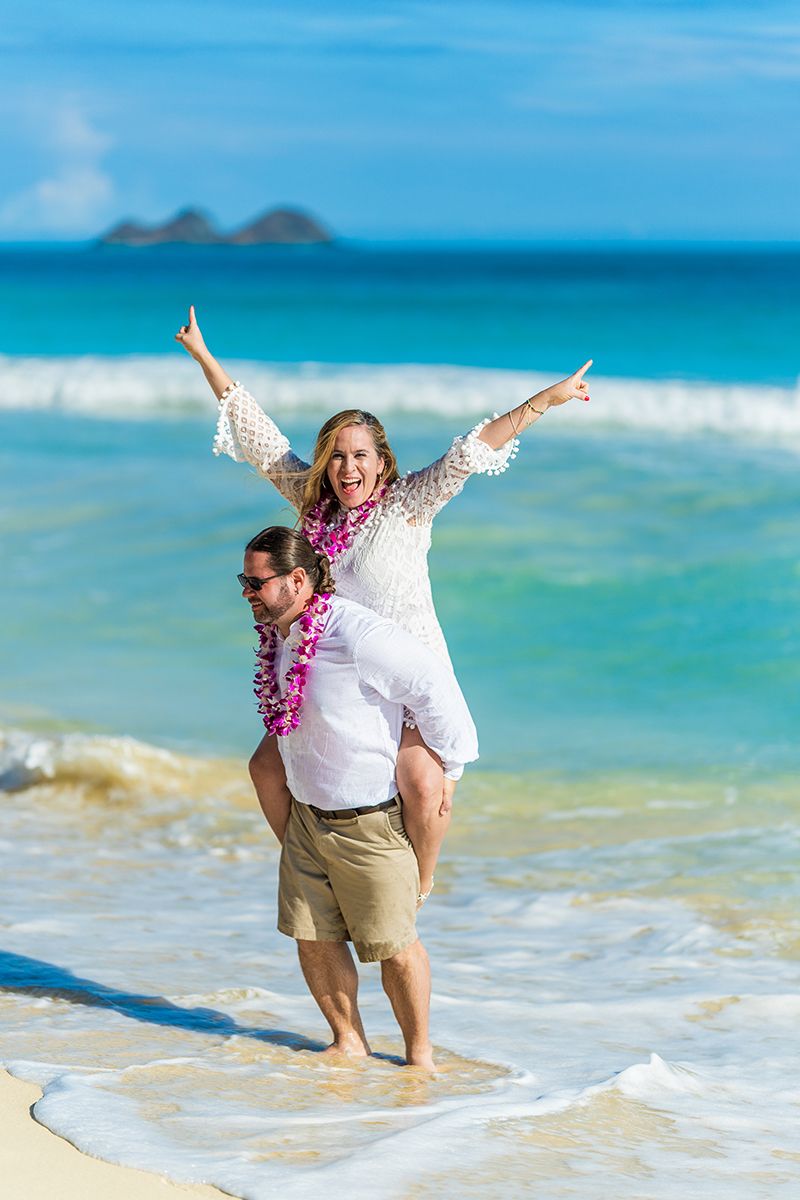 Bride doing the piggy back ride on her husband on the beach