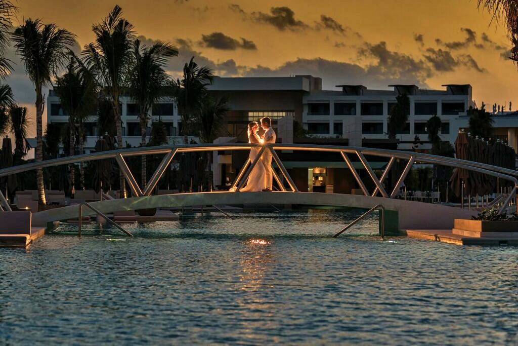Newlywed couple kissing a on a bridge over the pool at atelier hotel