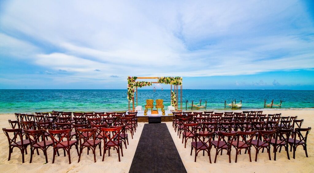 atelier weddings on the beach with an elevated ceremony platform and crossback wooden chairs