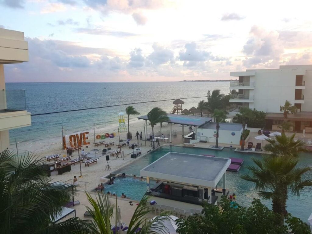 Aerial view of the pool and beach with a dinner party set up at the beach