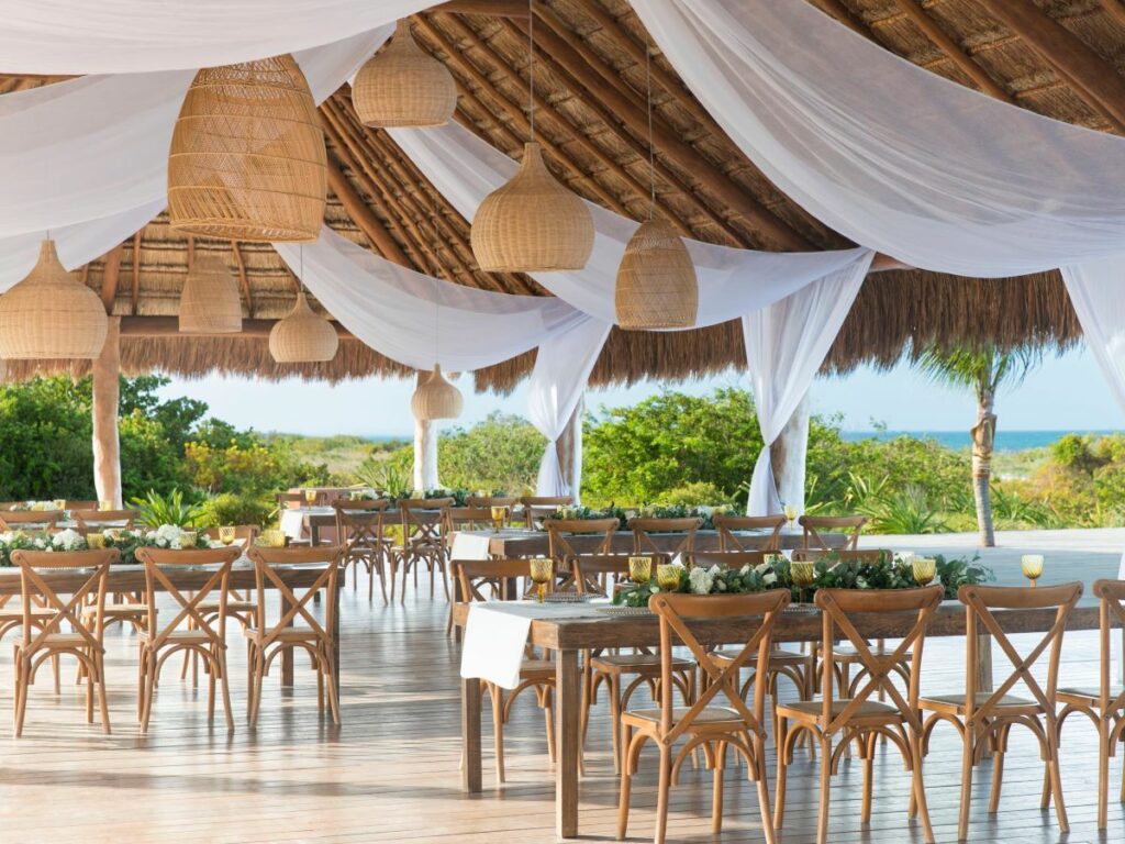 Wedding reception set up in a palapa deck with hanging lanterns and white drapes