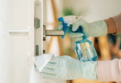gloved hands disinfecting door handle