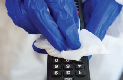 gloved hands disinfecting remote