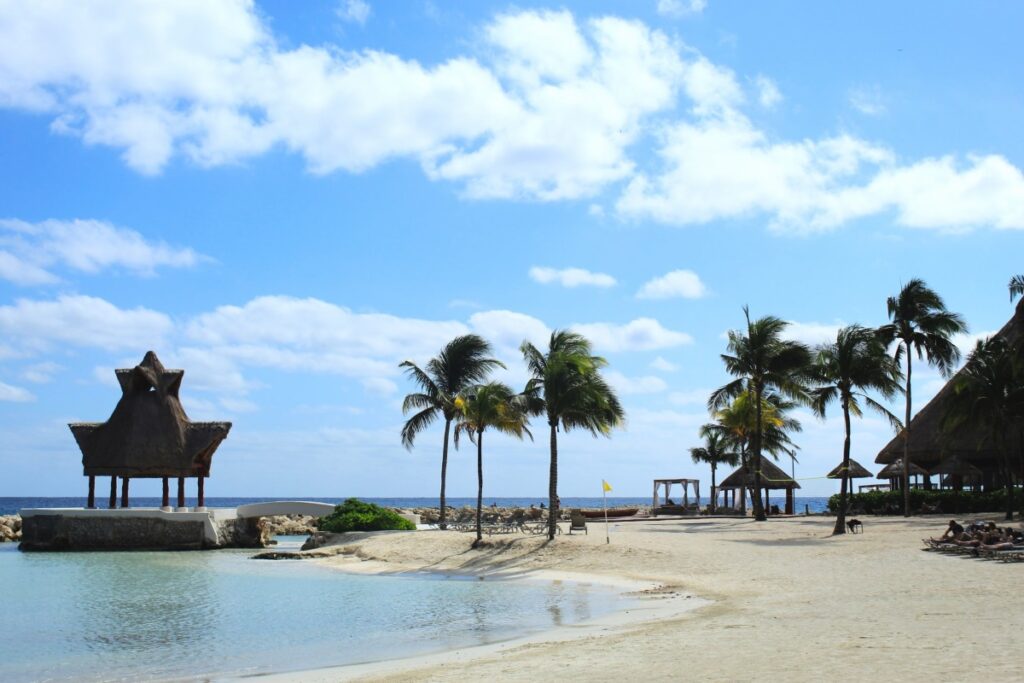a beach area of a resort in mexico with loungers and a wedding gazibo in the background