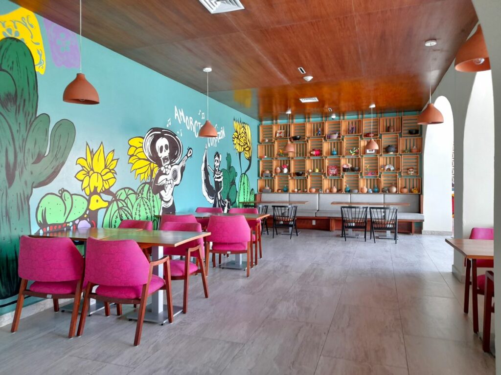 mexican restaurant with bring pink chairs and a mural painting with mexican skulls
