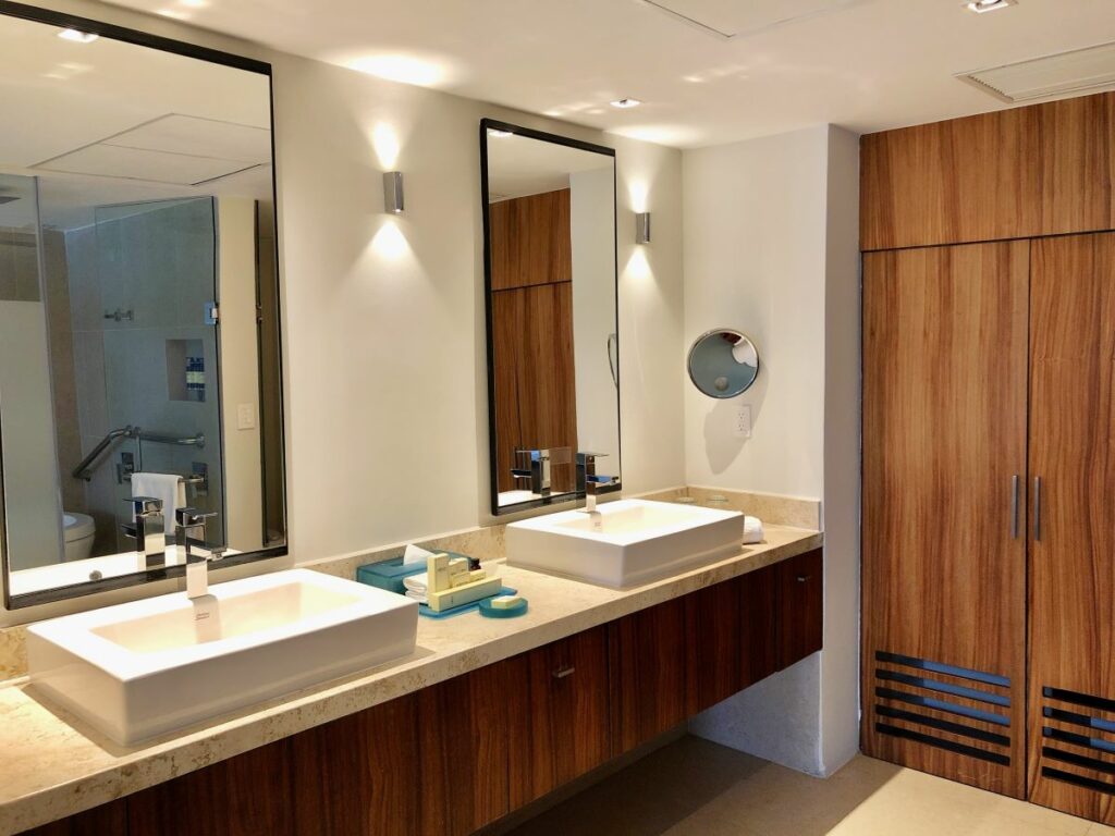 elegant hotel bathroom with two double sinks, large mirrors and wooden furniture