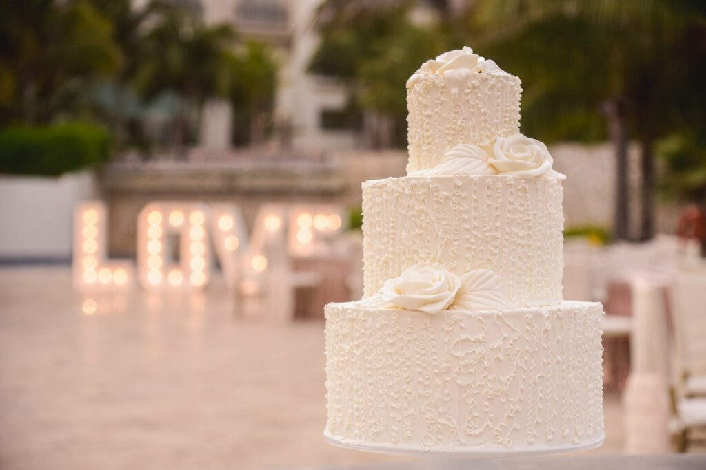 white wedding cake with love sign letters in the background