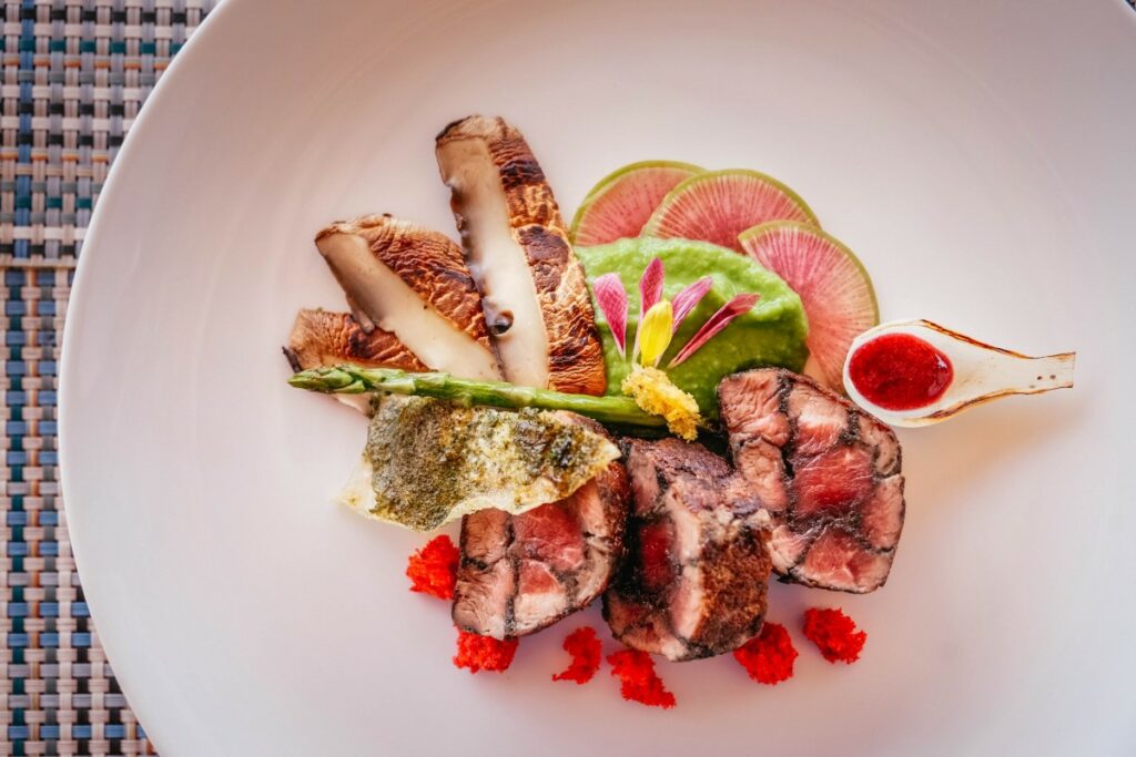 Meat filet with mushrooms, a green sauce and rose petals