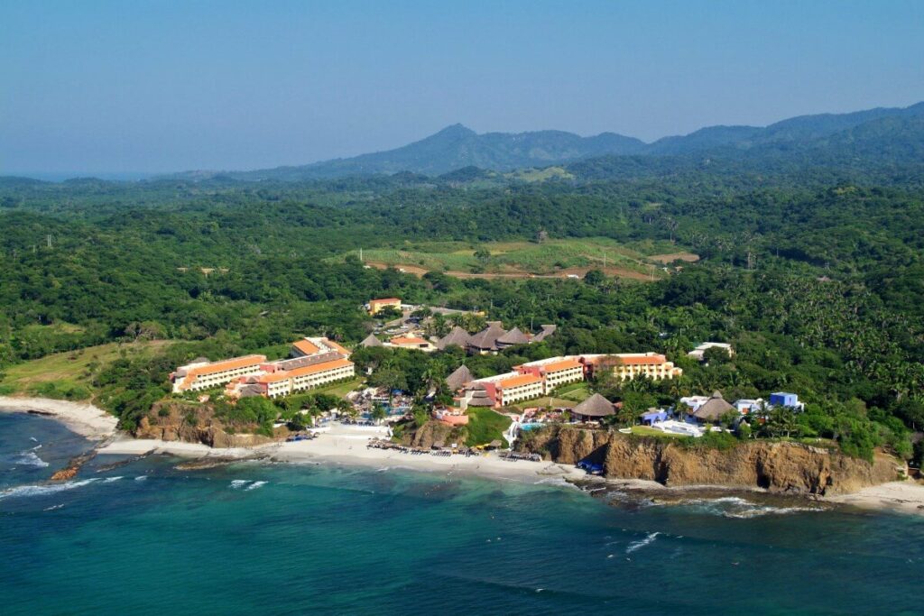 Aerial view of a beach resort with mountains and forest around it