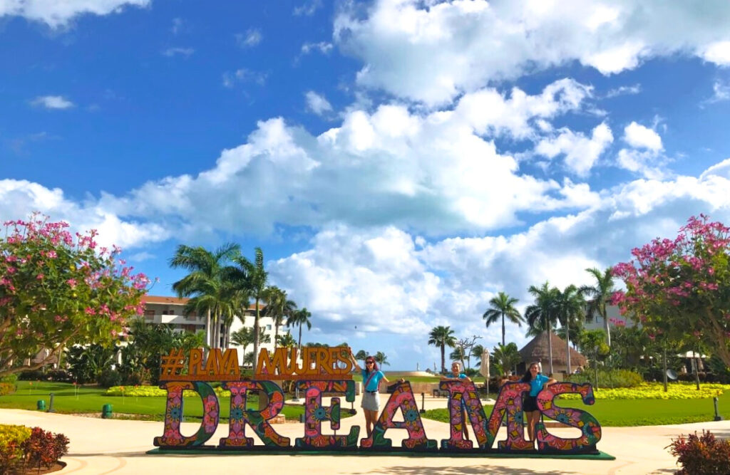 Hola Wedding team posing by the Dreams Playa Mujeres letters