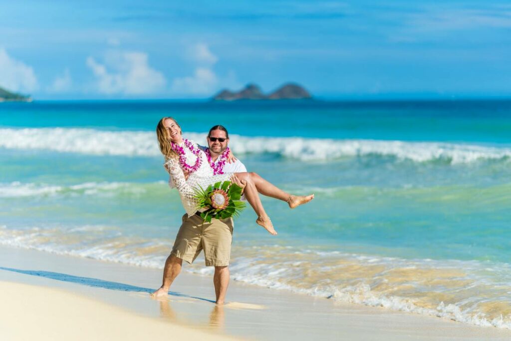 Groom carring her bride after the wedding ceremony on the beach