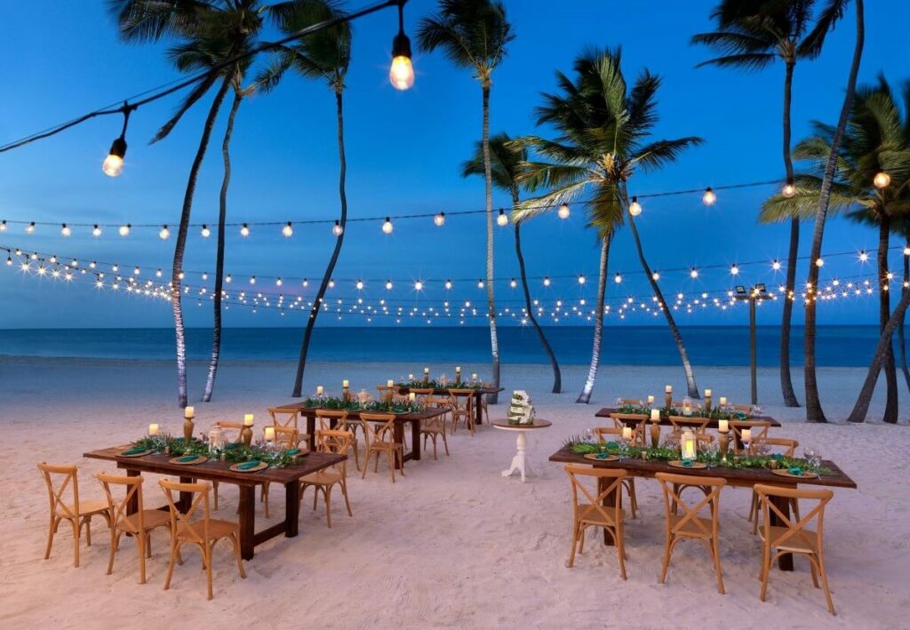 wedding reception set up on a beach with palmtrees and hanging lights