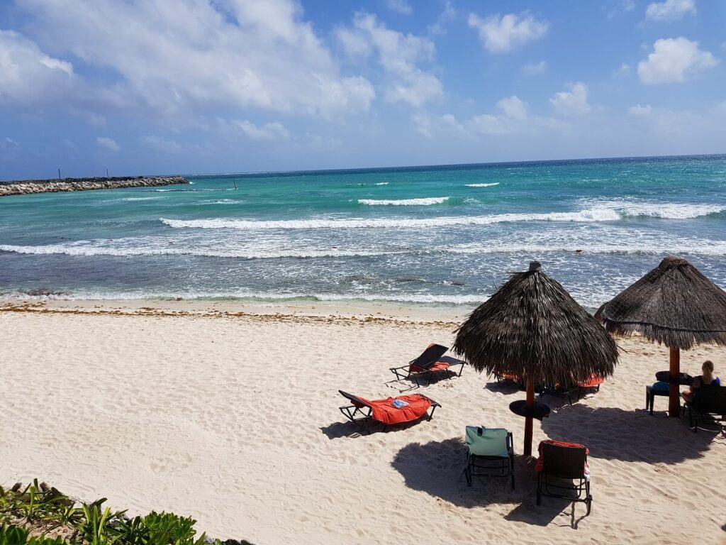 white sand beach with palapas for shade and loungers at now jade hotel