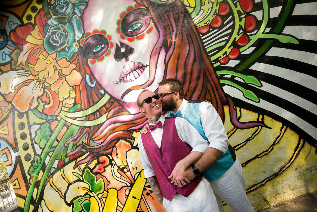 groom and groom in front of a colorful mural of a catarina