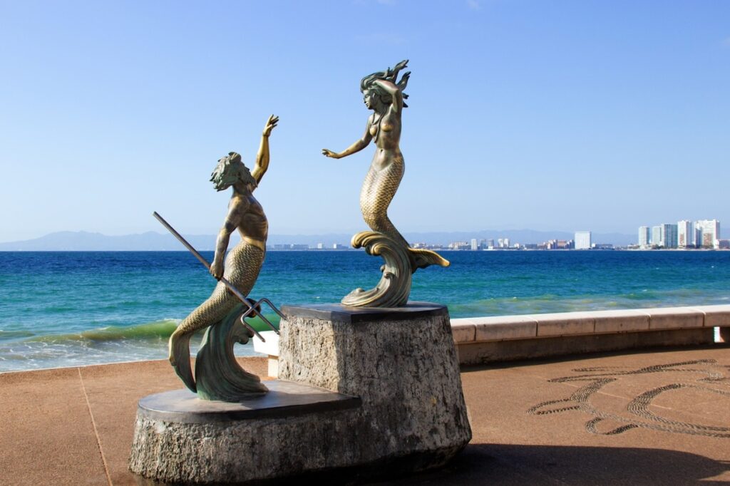 Scultpures of a mermaid couple in front of the sea