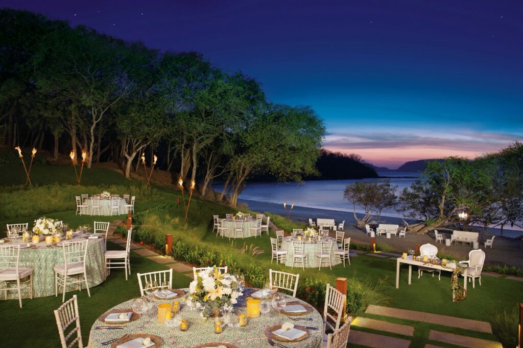 wedding reception at an ocean front garden with round tables with white tablecloths and flower centerpieces