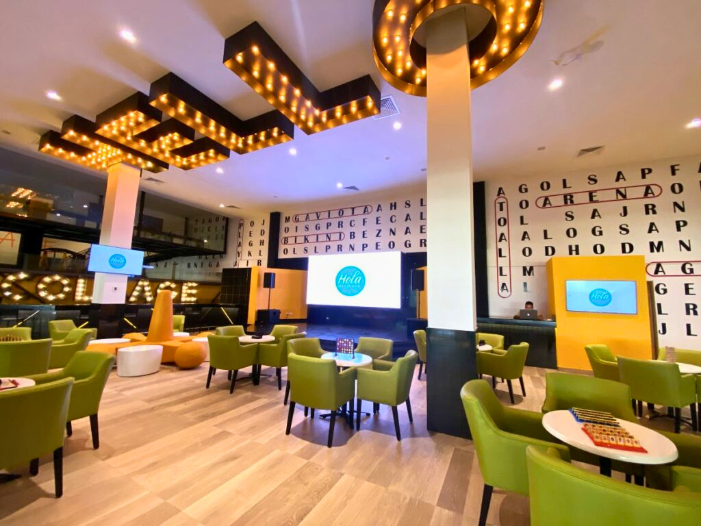 Game room with large screens and a hello sign on the ceiling