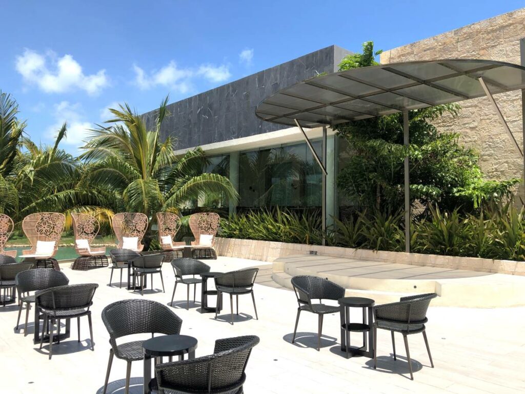 resort elegant restaurant with white chairs and hanging glass lights with a bar on the back