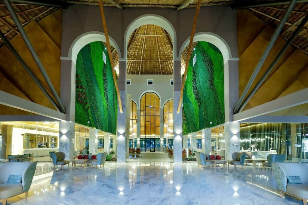 Resort lobbby with a big palapa roof, marble floor and large arch columns
