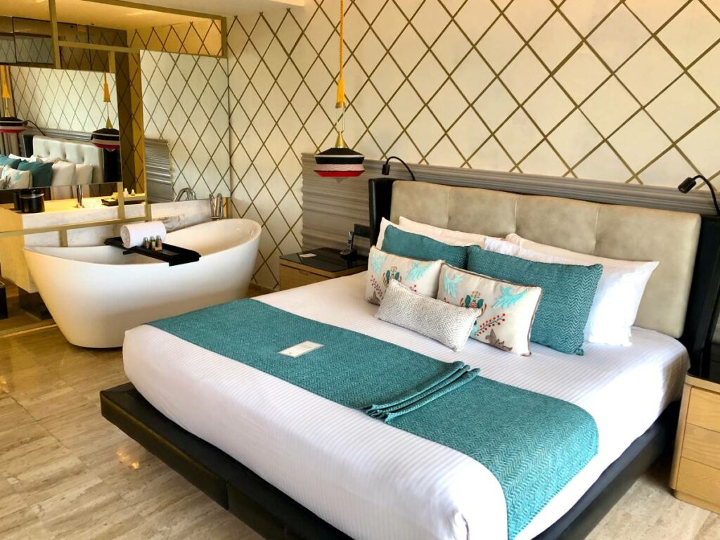 Hotel room with lots of mirrors, a bathtub and blue cushions and fabrics