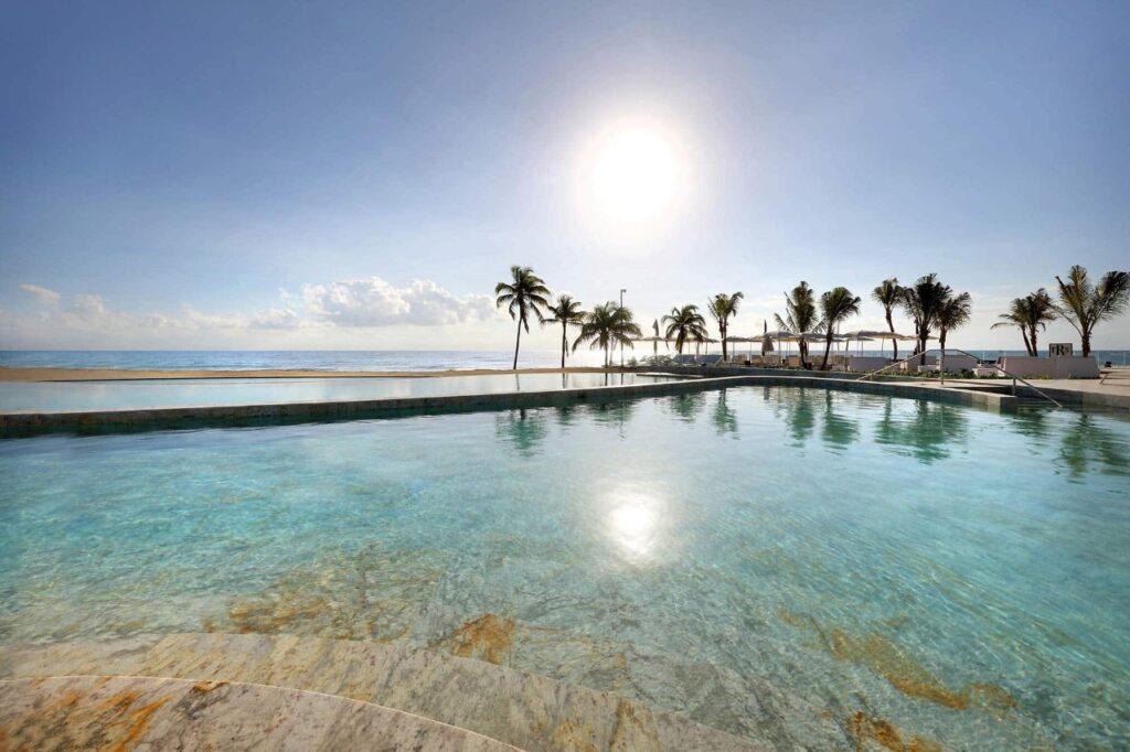 Infinity pool of a beach resort with palm trees is one way to how to cut down destination wedding costs