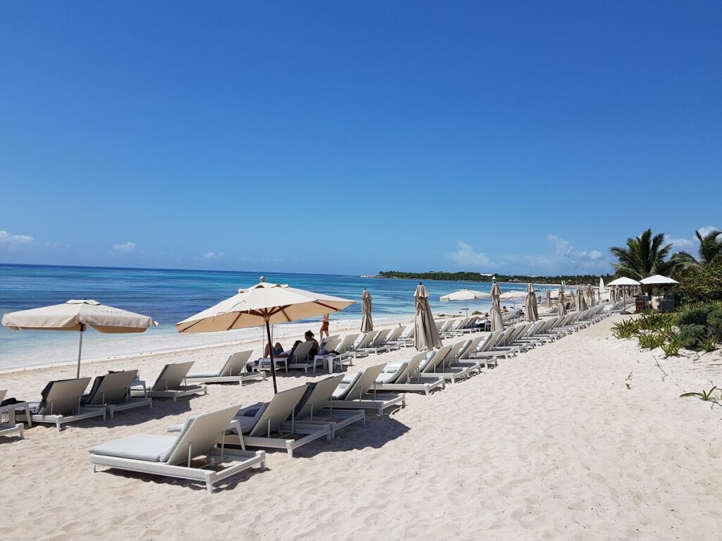 unico hotel beach area with white loungers, umbrellas and a calm ocean