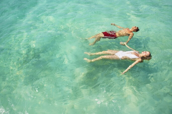 couple holding hands and floating in the ocean at one of the best all-inclusive honeymoon resorts in cancun