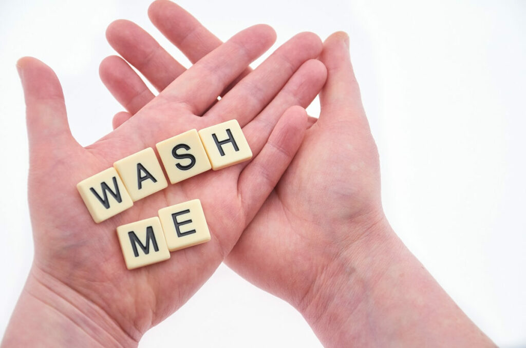 scrabble letters spelling wash me on someone's hands